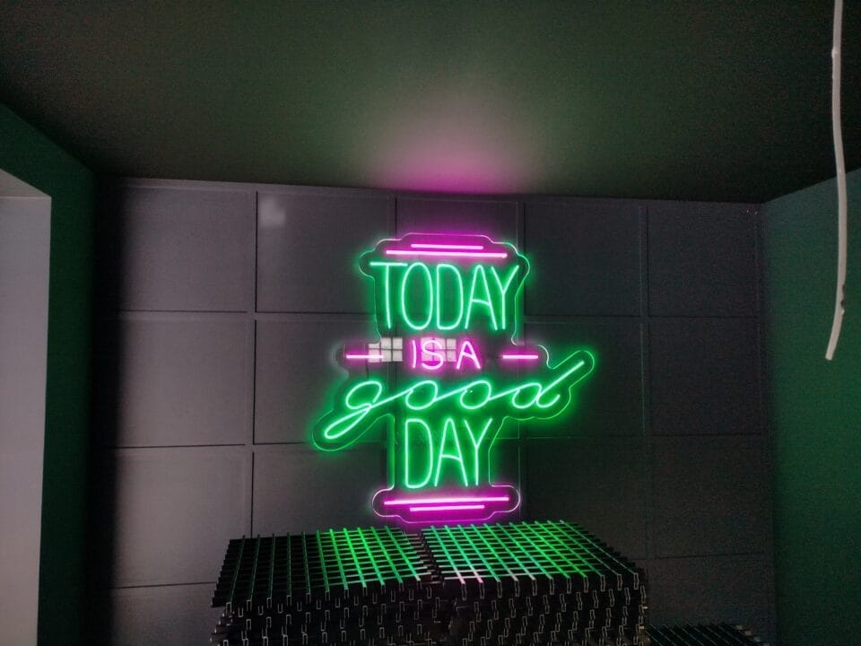 Neonled z napisem „Today is a good day” w kolorze zielonym z różowymi akcentami, zawieszony na ścianie.